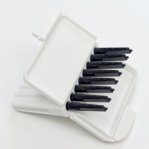 White plastic storage case with multiple black razor blade attachments aligned in a row, viewed diagonally.